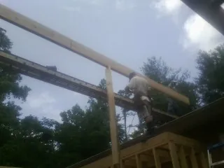 Carpenter setting a ridge beam over a new addition frame — Ice Dam Removal by Roofing Brothers in Atkins
