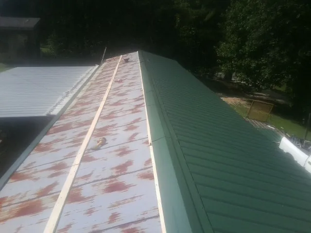 Old rusted panels beside newly installed green metal roofing — Wind Damage Roof Repair by Roofing Brothers in Atkins