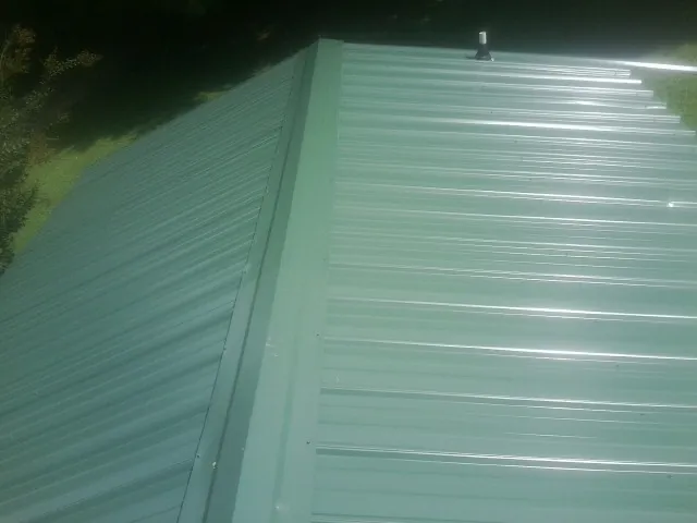 New green metal panels meeting at the ridge of a roof — Flat Roof Repair work by our crew in Atkins