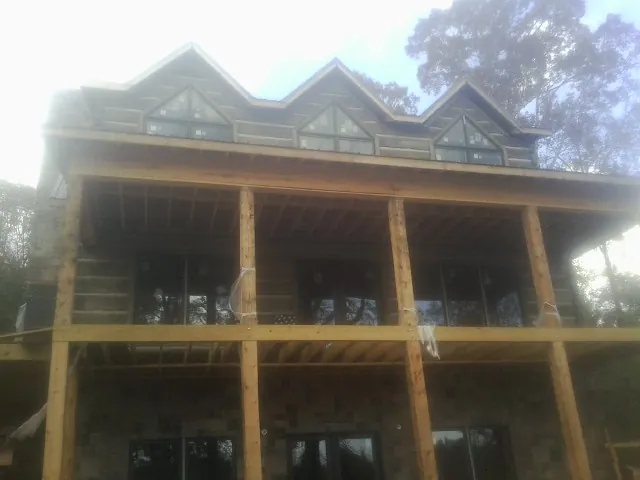 Dormers and porch framing on a large log home under construction — Roof Coating work by our crew in Atkins