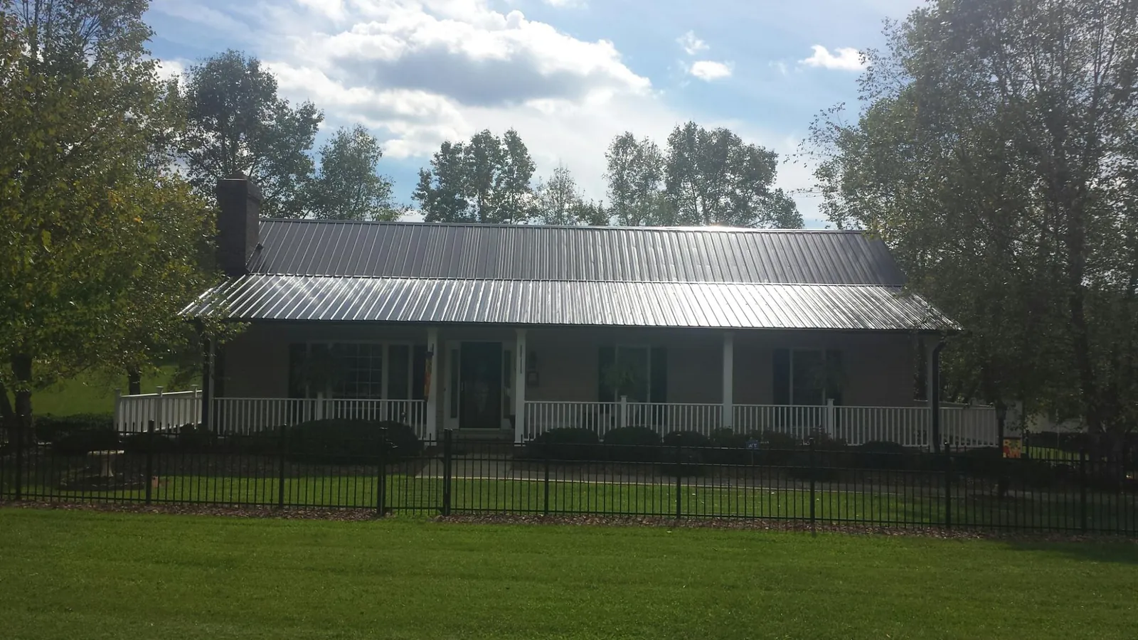 Gray metal roof on a brick ranch with a full width front porch — Gutter Guard Installation work by our crew in Atkins