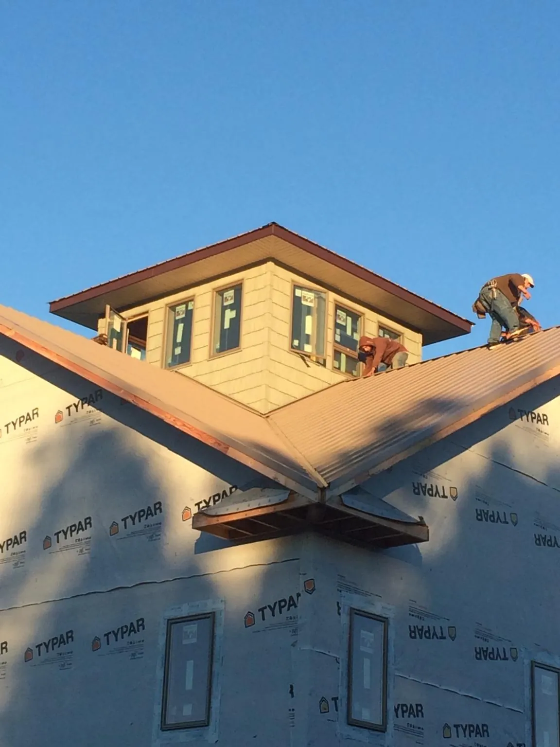Roofers working around a rooftop cupola on a new metal roof at sunset — Roof Waterproofing in Atkins by Roofing Brothers